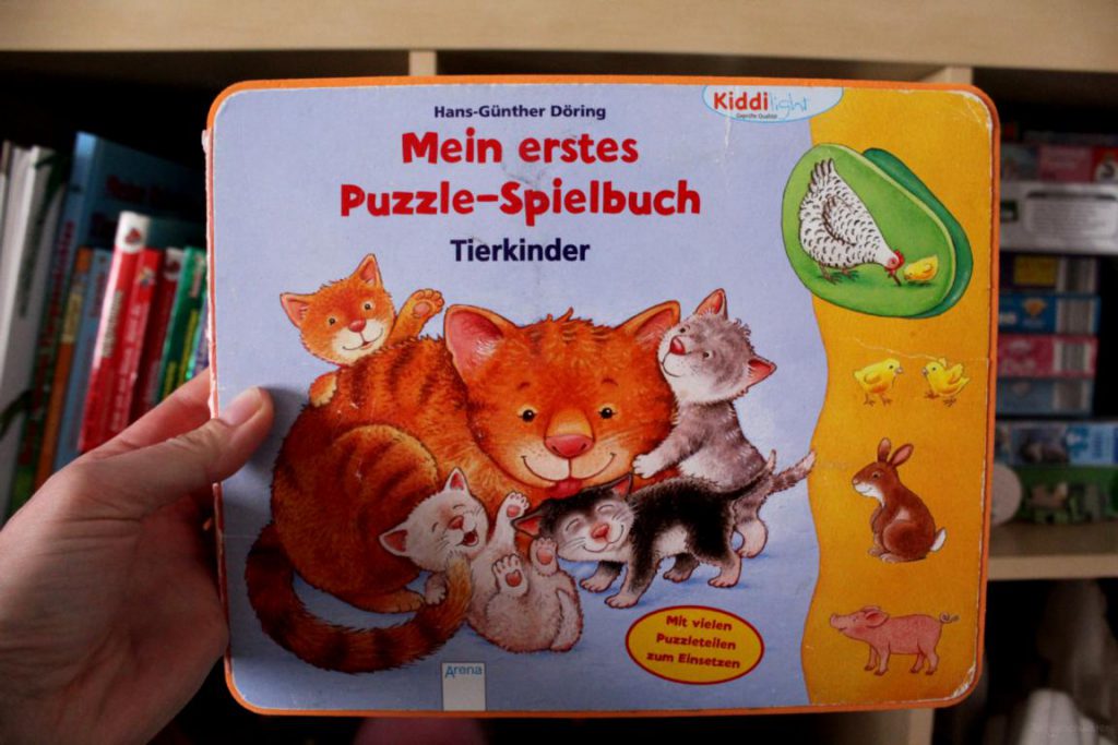 Kinderbuch Mein erstes Puzzel-Spielbuch vor einem Spielzeugschrank gehalten
