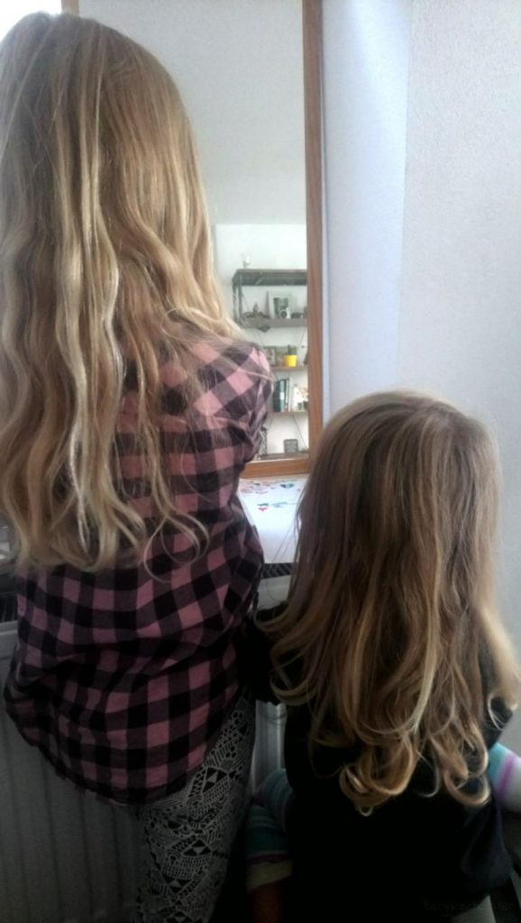 Zwei Mädchen von hinten vor einem Spiegel