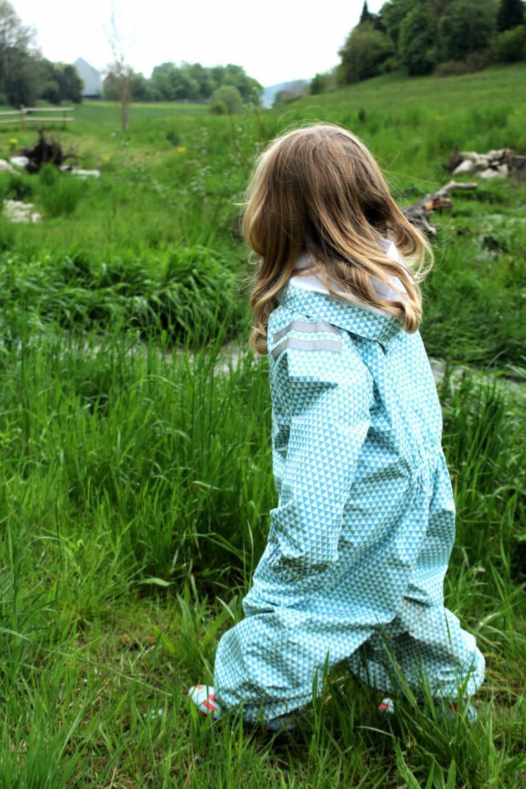 Mädchen steht auf einer Wiese am Bach