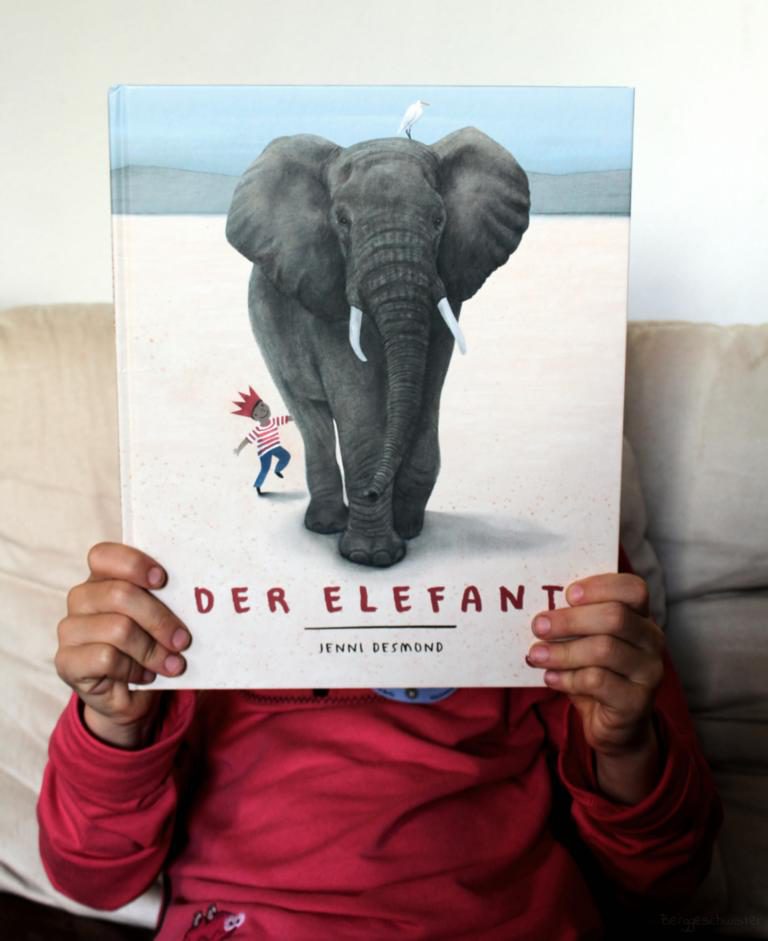 Kind hält der Buch Der Elefant von Jenni Desmond hoch