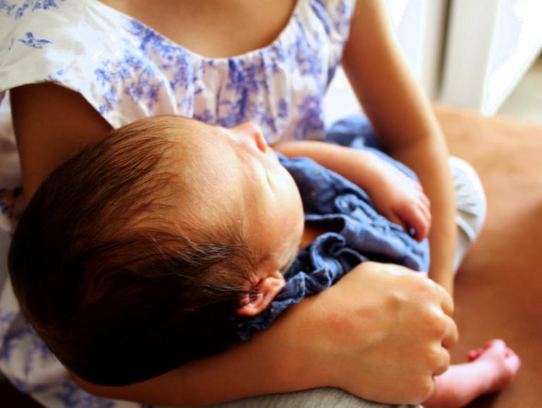 neugeborenes Baby im Arm seiner großen Schwester